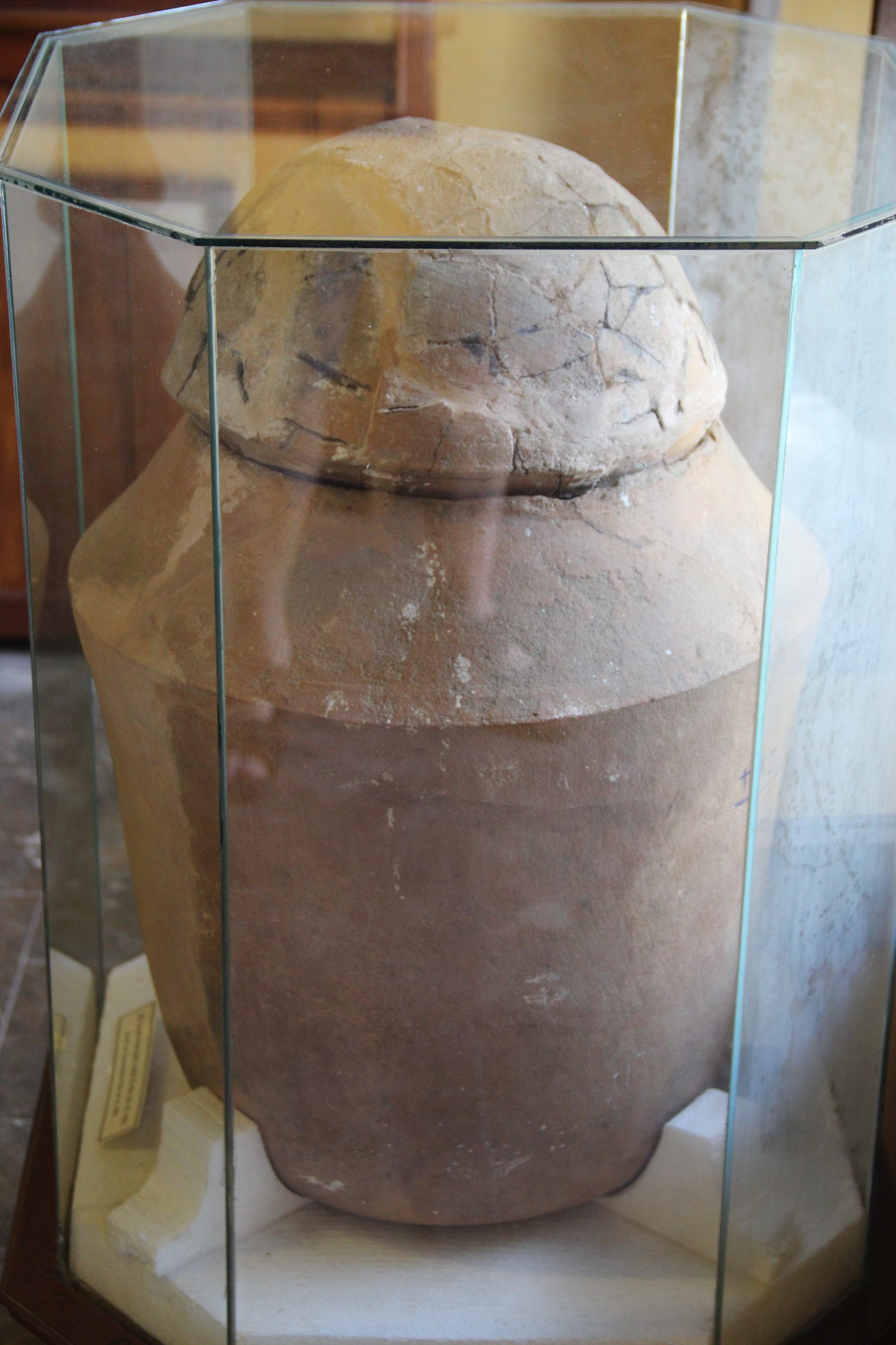 A Sa Huỳnh burial jar with a domed lid, displayed in a glass case at the Sa Huỳnh Culture Museum, Hội An.